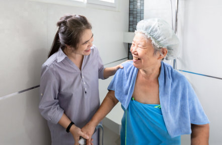 a female caregiver assisting an elderly woman